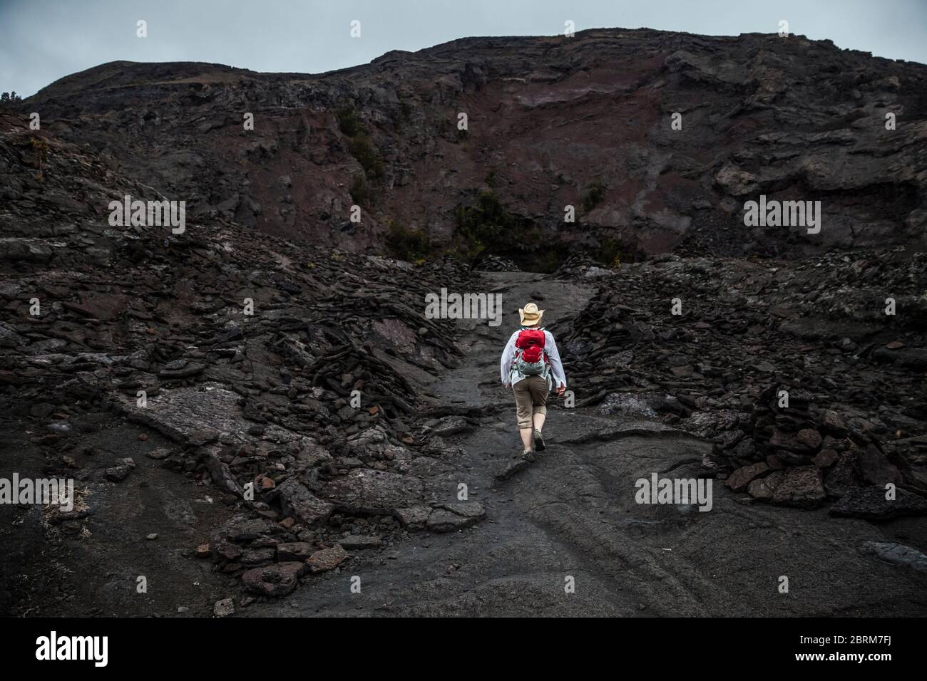 Eine Frau geht in Richtung Pu’U PUA’i oder dem Gushing Hill, einem vulkanischen Merkmal im Hawaii Volcanoes National Park, Hawai'i, USA Stockfoto