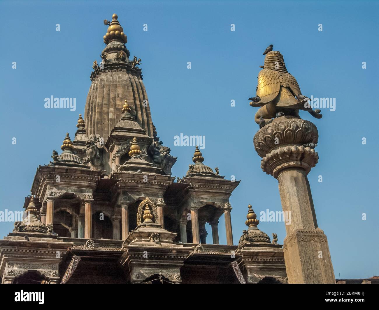 Nepal, Kathmandu. Bunte Straßenszenen auf dem mittelalterlichen Durbar-Platz in der antiken Stadt Patan mit Blick auf die mythische Vogelmann Garuda-Säule und den Krishna Mandir-Tempel, der von König Siddhirarsingh Malla im 17. Jahrhundert erbaut wurde Stockfoto