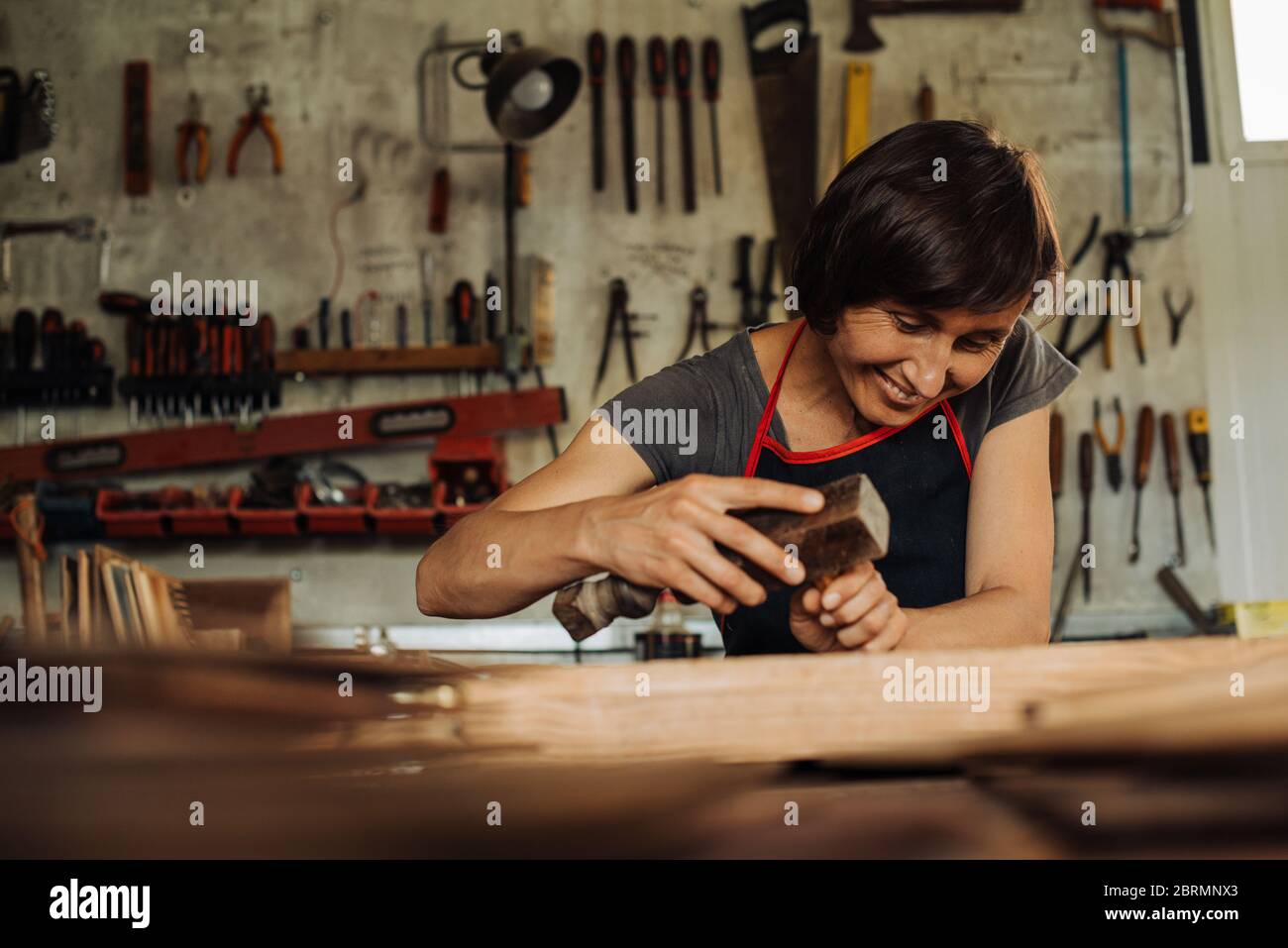 Holzarbeiterin in der Werkstatt, Werkzeuge im Hintergrund Stockfoto