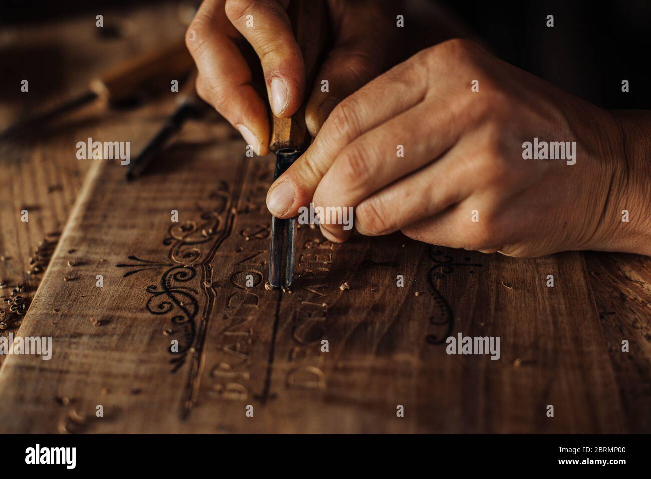 Nahaufnahme Prozess der dekorativen Holzgravur mit Handwerkzeugen Stockfoto