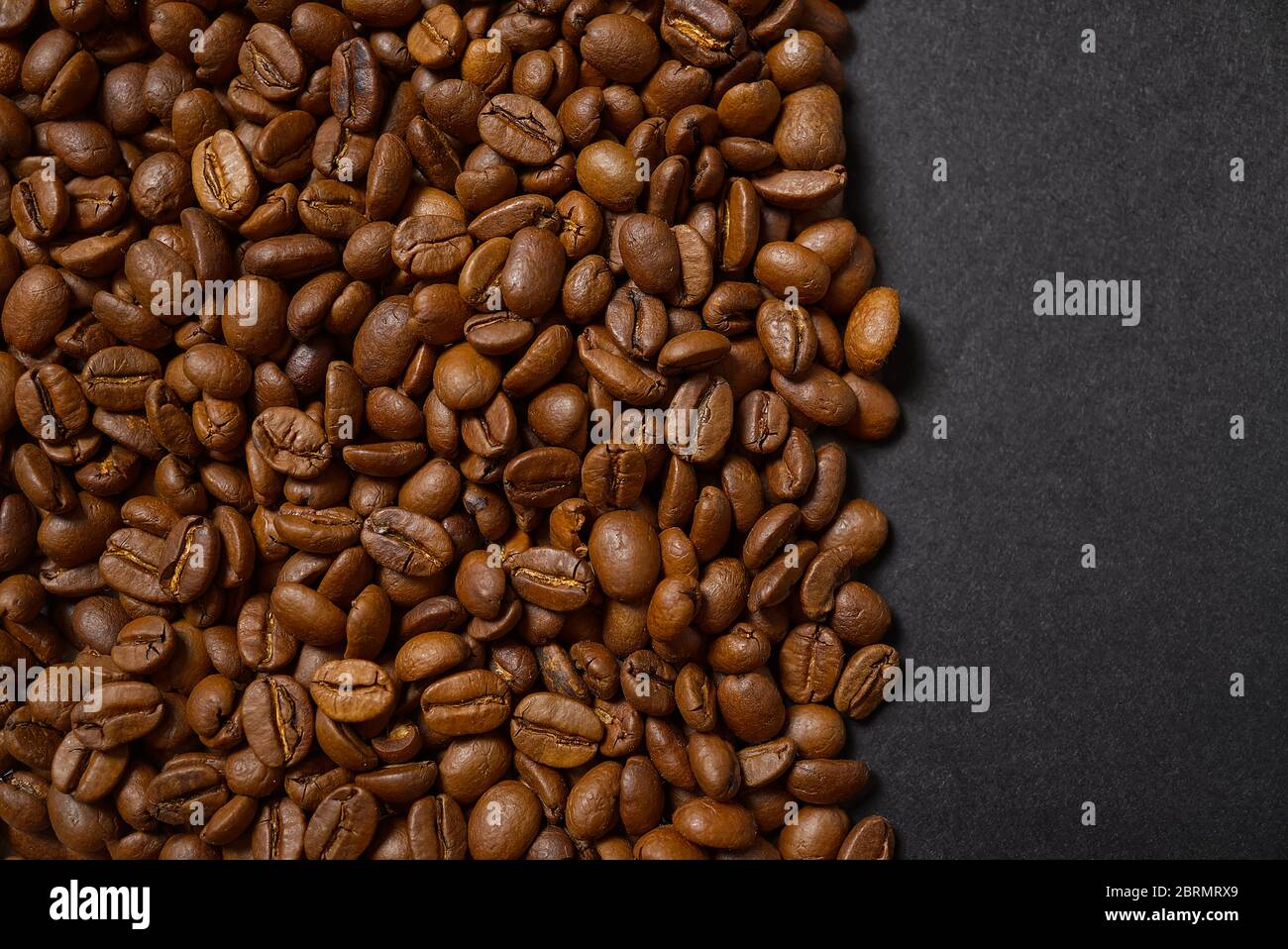 Textur der Kaffeebohnen. Geröstete Kaffeebohnen Hintergrund. Schließen Sie Kaffeebohnen mit Kopierraum auf schwarzem Hintergrund. Stockfoto