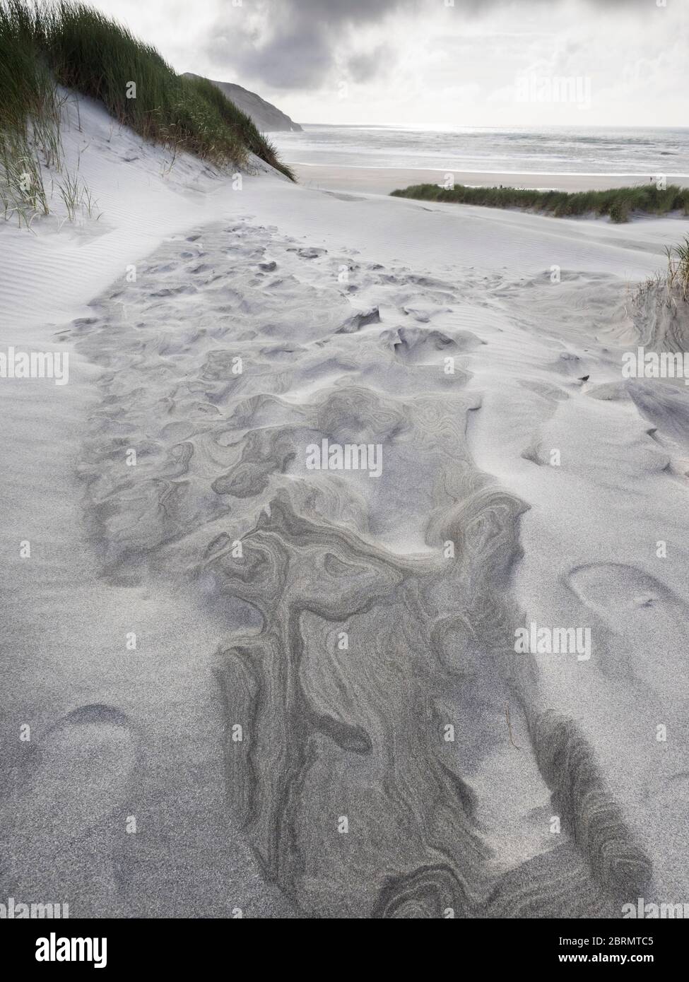 Fußabdrücke auf einer Sanddüne am Windswept Wharariki Beach und den Archway Islands, Puponga, Tasman, Neuseeland Stockfoto