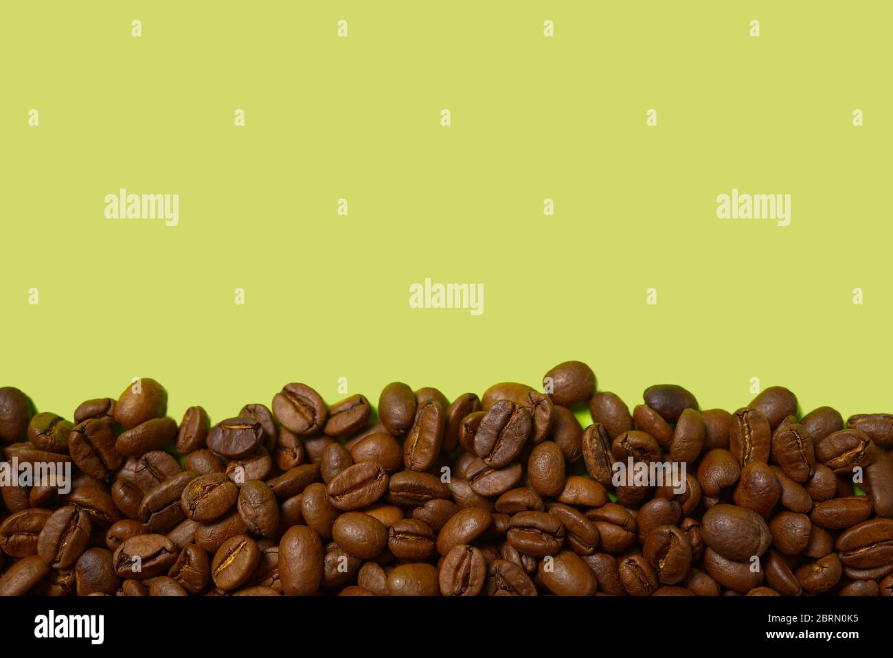 Textur der Kaffeebohnen. Geröstete Kaffeebohnen Hintergrund. Schließen Sie Kaffeebohnen mit Copy Space auf grünem Hintergrund. Stockfoto