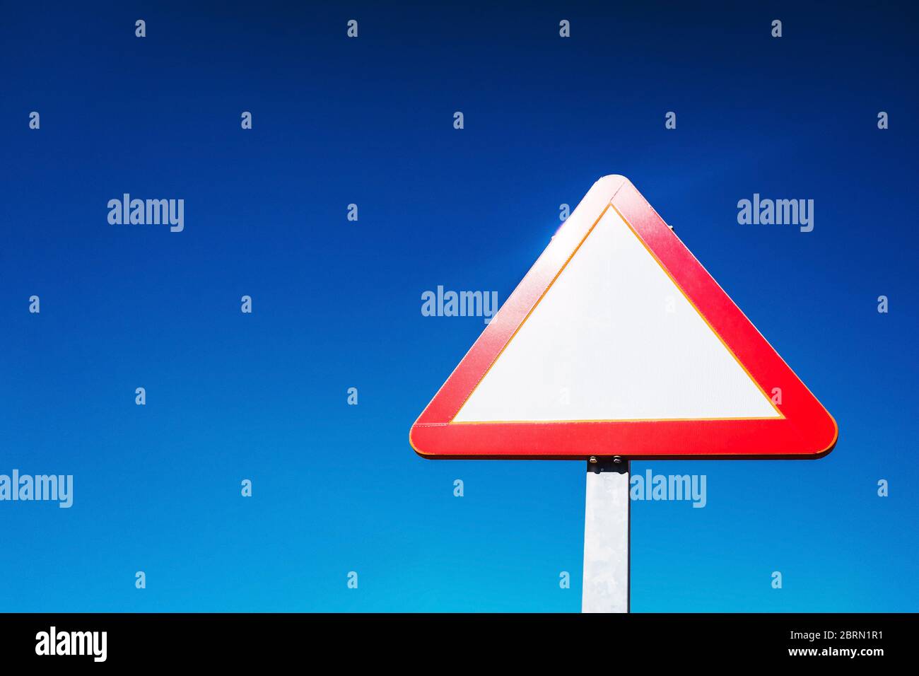 Dreieckiges Verkehrszeichen, leer, Warnhinweis vor blauem Himmel Hintergrund und negativer Raum, um Text hinzuzufügen. Stockfoto