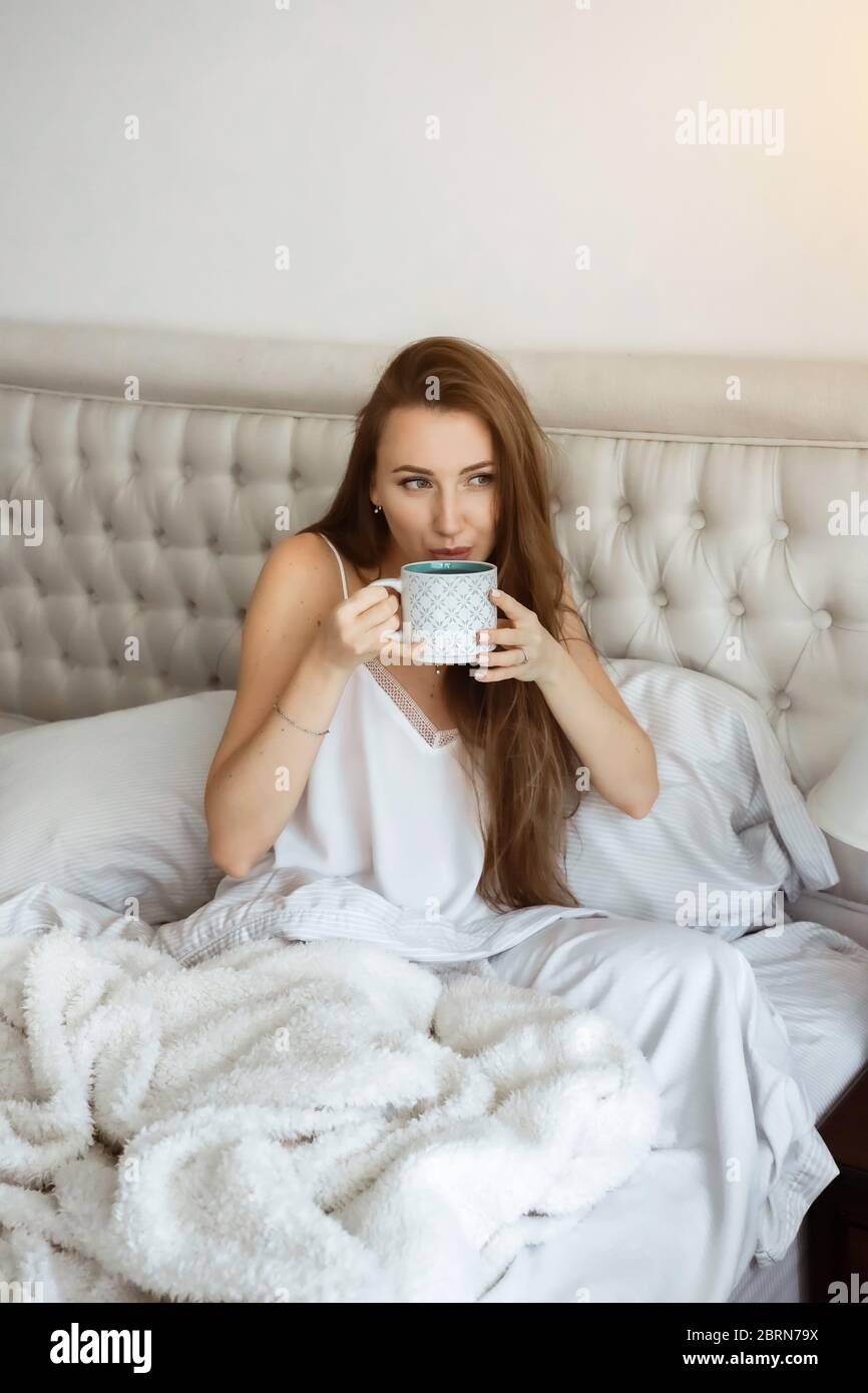 Zuhause Selbstisolierung, Schlafenszeit. Anpassung der Menschen während der Covid-19-Pandemiequarantäne. Mädchen im Bett, trinkt Kaffee Stockfoto