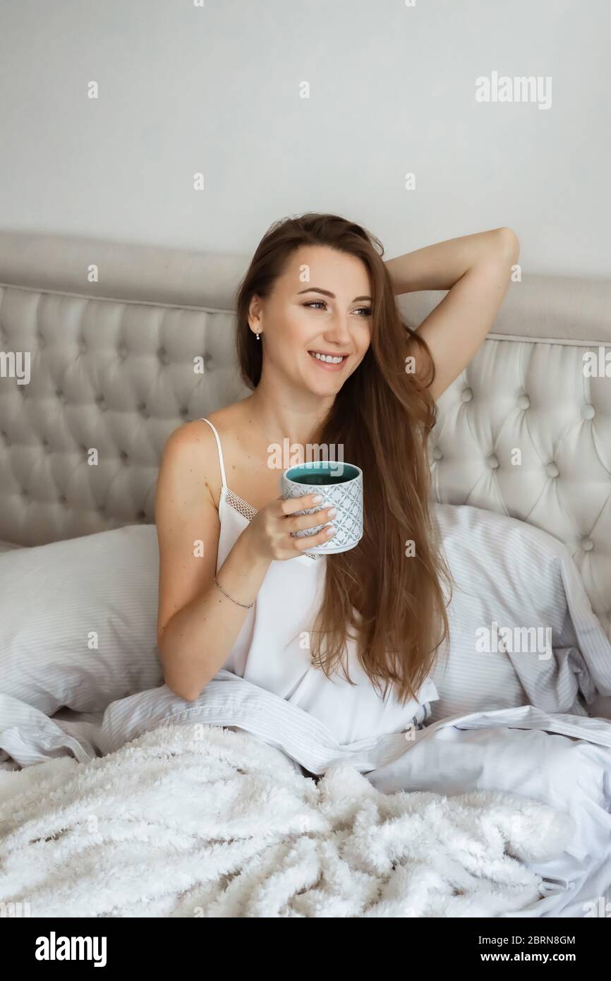 Zuhause Selbstisolierung, Schlafenszeit. Anpassung der Menschen während der Covid-19-Pandemiequarantäne. Mädchen im Bett, trinkt Kaffee Stockfoto