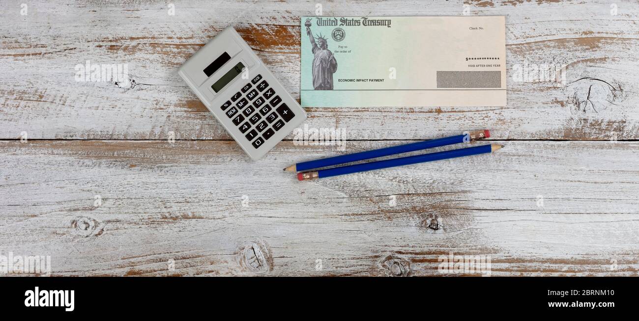 Ökonomische Auswirkung Stimulus Check auf weißem Holz Desktop mit Bleistiften und Rechner. Stockfoto