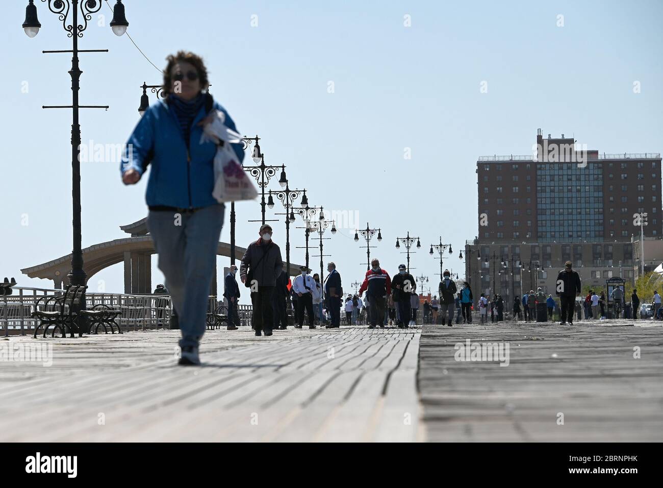 New York City, USA. Mai 2020. Einige tragen Gesichtsmasken und andere nicht in der Zeit der COVID-19 Pandemie, Menschen gehen entlang der Coney Island Promenade in Brooklyn Bezirk von New York City, NY, 21. Mai 2020. Die NYPD kündigte an, dass sie am Memorial Day Wochenende die Strände patrouillieren wird, um die soziale Distanz zu genießen und Masken auszuteilen, und sagte, Strandbesucher können nur knöcheltief ins Wasser gehen, kein Schwimmen ist erlaubt, aber Surfen wird erlaubt sein. (Anthony Behar/Sipa USA) Credit: SIPA USA/Alamy Live News Stockfoto