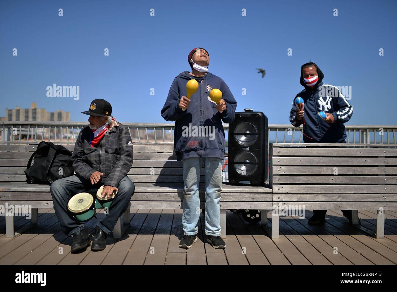 New York City, USA. Mai 2020. Eine Gruppe von Freunden begleitet Musik von einem Redner mit Bongos und Maracas, während sie den Geburtstag eines Freundes auf dem Pier von Coney Island im Brooklyn-Bezirk von New York City, NY, am 21. Mai 2020 feiern. Die NYPD kündigte an, dass sie am Memorial Day Wochenende die Strände patrouillieren wird, um die soziale Distanz zu genießen und Masken auszuteilen, und sagte, Strandbesucher können nur knöcheltief ins Wasser gehen, kein Schwimmen ist erlaubt, aber Surfen wird erlaubt sein. (Anthony Behar/Sipa USA) Credit: SIPA USA/Alamy Live News Stockfoto