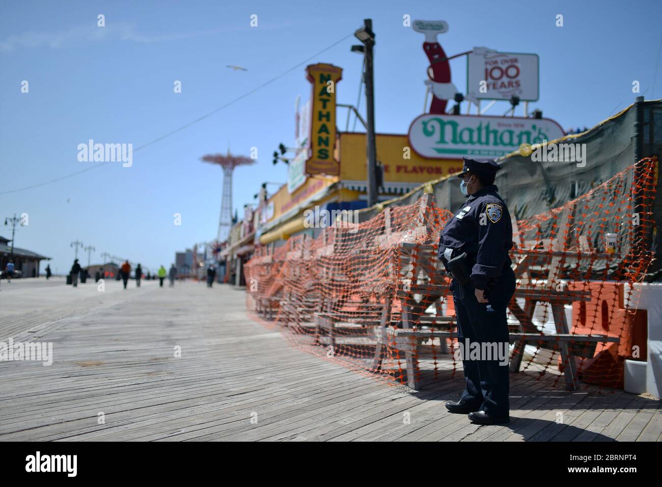 In der Zeit der COVID-19-Pandemie trägt ein Sicherheitsbeauftragter der NYPD-Schule die Strandpromenade von Coney Island, um die Regeln der sozialen Distanz zu wahren und schützende Gesichtsmasken auszuhändigen.Er befindet sich im Stadtteil New York City, New York, 21. Mai 2020. Die NYPD kündigte an, dass sie am Memorial Day Wochenende die Strände patrouillieren wird, um die soziale Distanz zu genießen und Masken auszuteilen, und sagte, Strandbesucher können nur knöcheltief ins Wasser gehen, kein Schwimmen ist erlaubt, aber Surfen wird erlaubt sein. (Anthony Behar/Sipa USA) Stockfoto