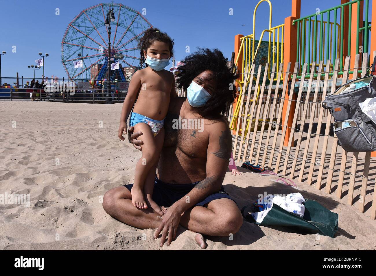 New York City, USA. Mai 2020. Beide tragen zur Zeit der COVID-19-Pandemie eine Gesichtsmaske und Jose Flores aus Brooklyn hält seinen dreijährigen Sohn Maki, während sie den Tag am Coney Island Beach im Brooklyn-Bezirk von New York City, NY, am 21. Mai 2020 verbringen. Die NYPD kündigte an, dass sie am Memorial Day Wochenende die Strände patrouillieren wird, um die soziale Distanz zu genießen und Masken auszuteilen, und sagte, Strandbesucher können nur knöcheltief ins Wasser gehen, kein Schwimmen ist erlaubt, aber Surfen wird erlaubt sein. (Anthony Behar/Sipa USA) Credit: SIPA USA/Alamy Live News Stockfoto