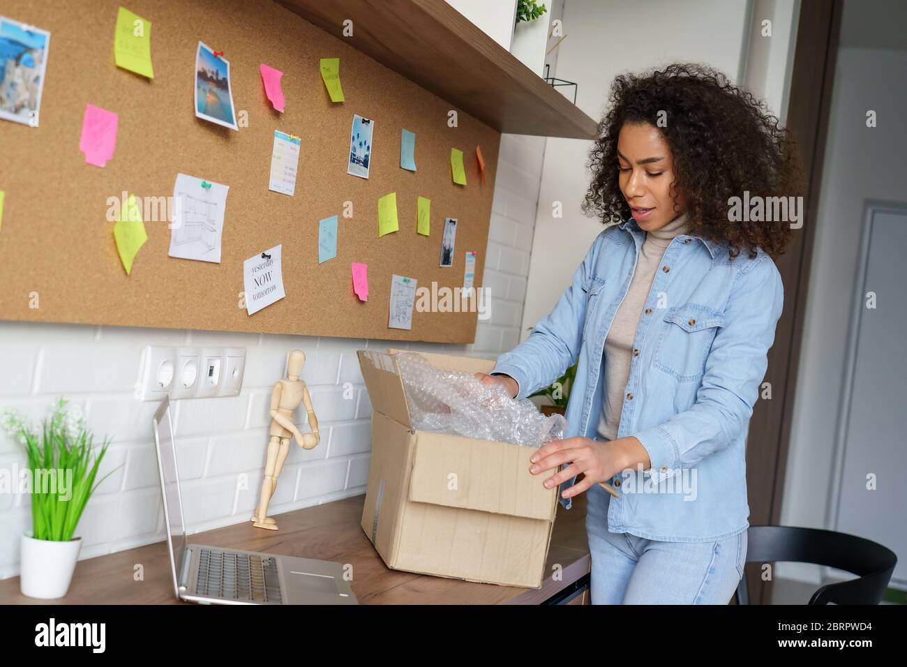 Junge afroamerikanische Frau Kunde Öffnung Paketkasten zu Hause. Stockfoto