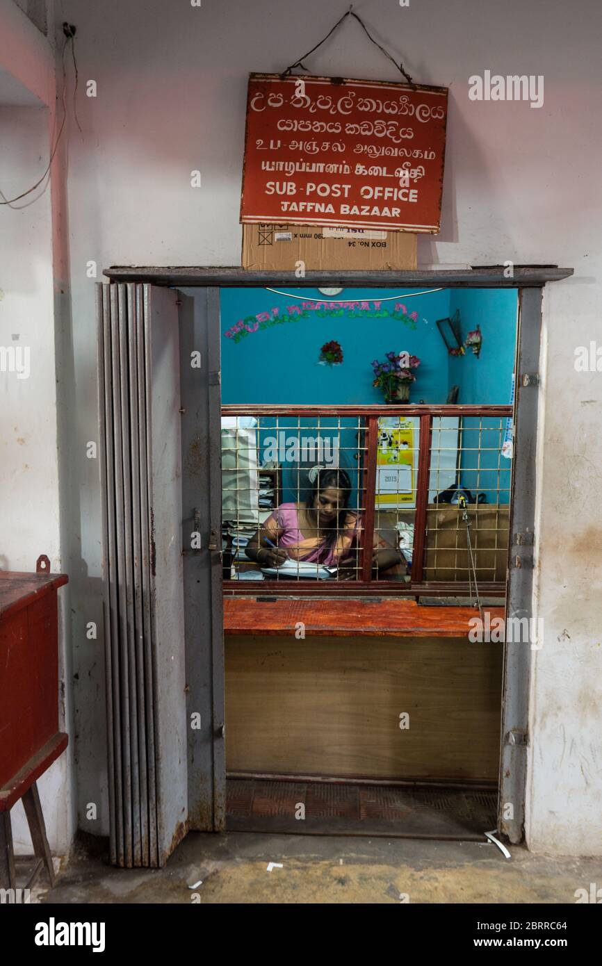 Jaffna / Sri Lanka - 15. August 2019: Frau, die im Postamt arbeitet, durch den Stand gesehen Stockfoto