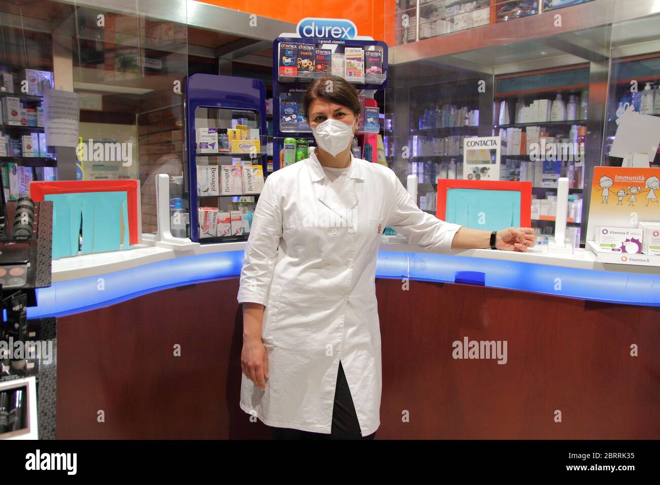 Ein Arzt an Ihrem Apothekenschalter während des covid-19 Notfalls. Handschuhe, Masken und Verkleidungen am Schalter zum Schutz von Kunden und Apothekenpersonal Stockfoto