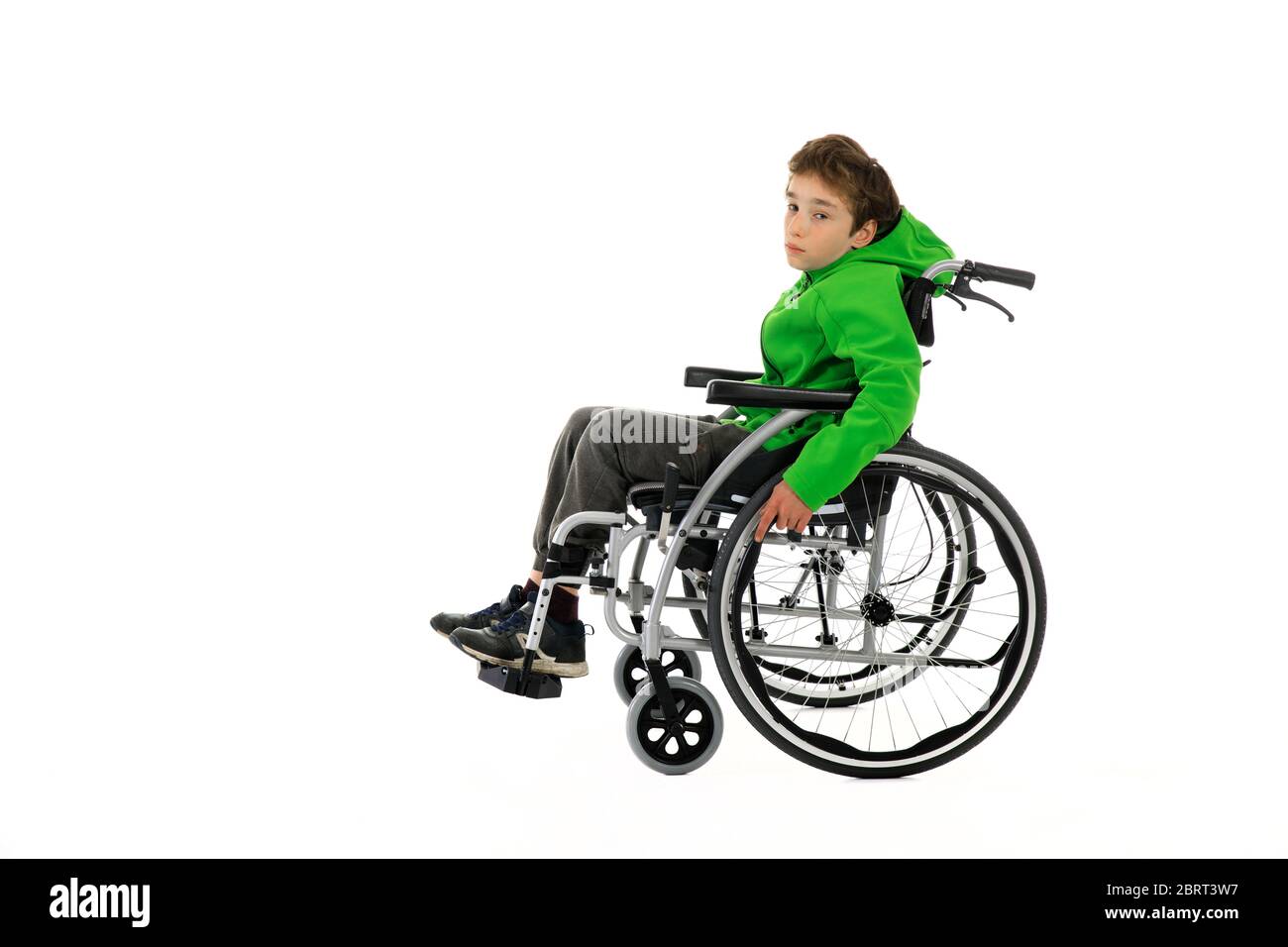 Kleiner Junge im Rollstuhl auf weißem Hintergrund, Junge sitzt in einem Rollstuhl auf weißem Hintergrund. Krankenhauspatient mit Behinderung Stockfoto