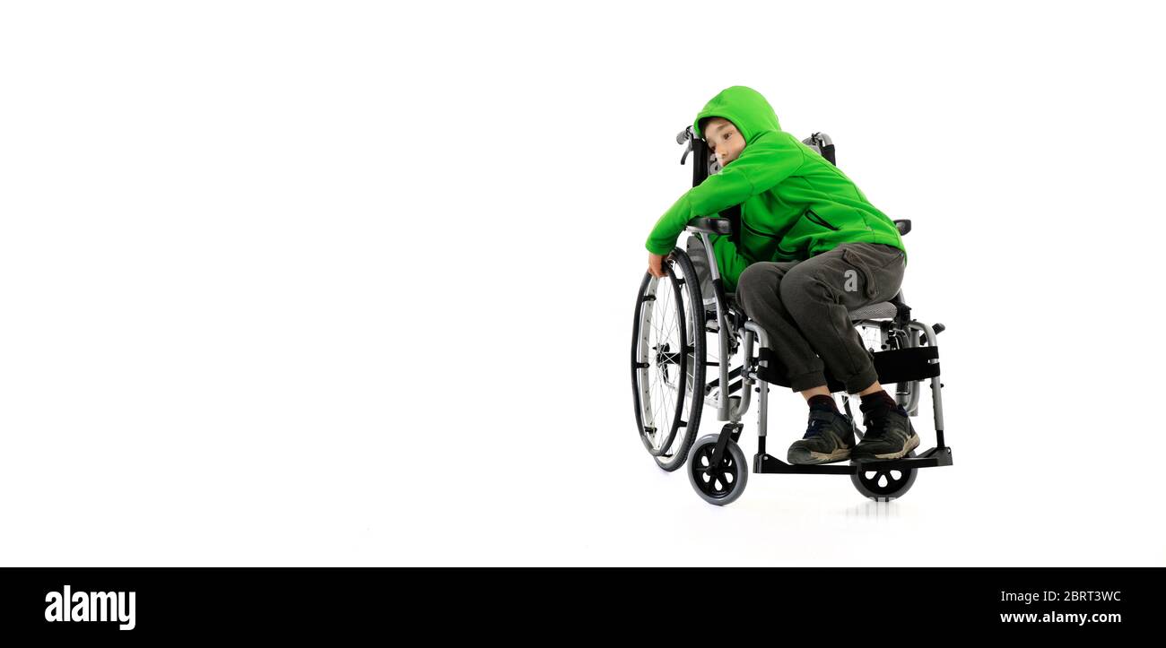 Kleiner Junge im Rollstuhl auf weißem Hintergrund, Junge sitzt in einem Rollstuhl auf weißem Hintergrund. Krankenhauspatient mit Behinderung Stockfoto