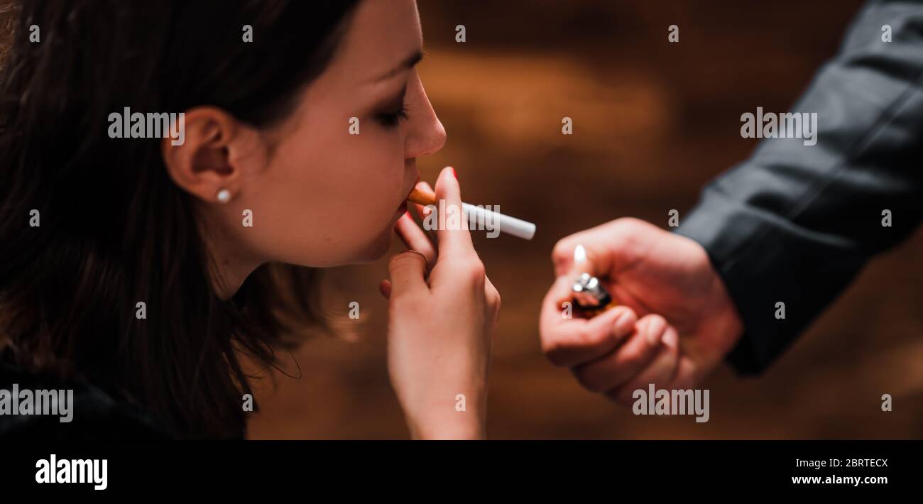 Ein Herr zündet eine Zigarette einer schönen Frau an Stockfoto