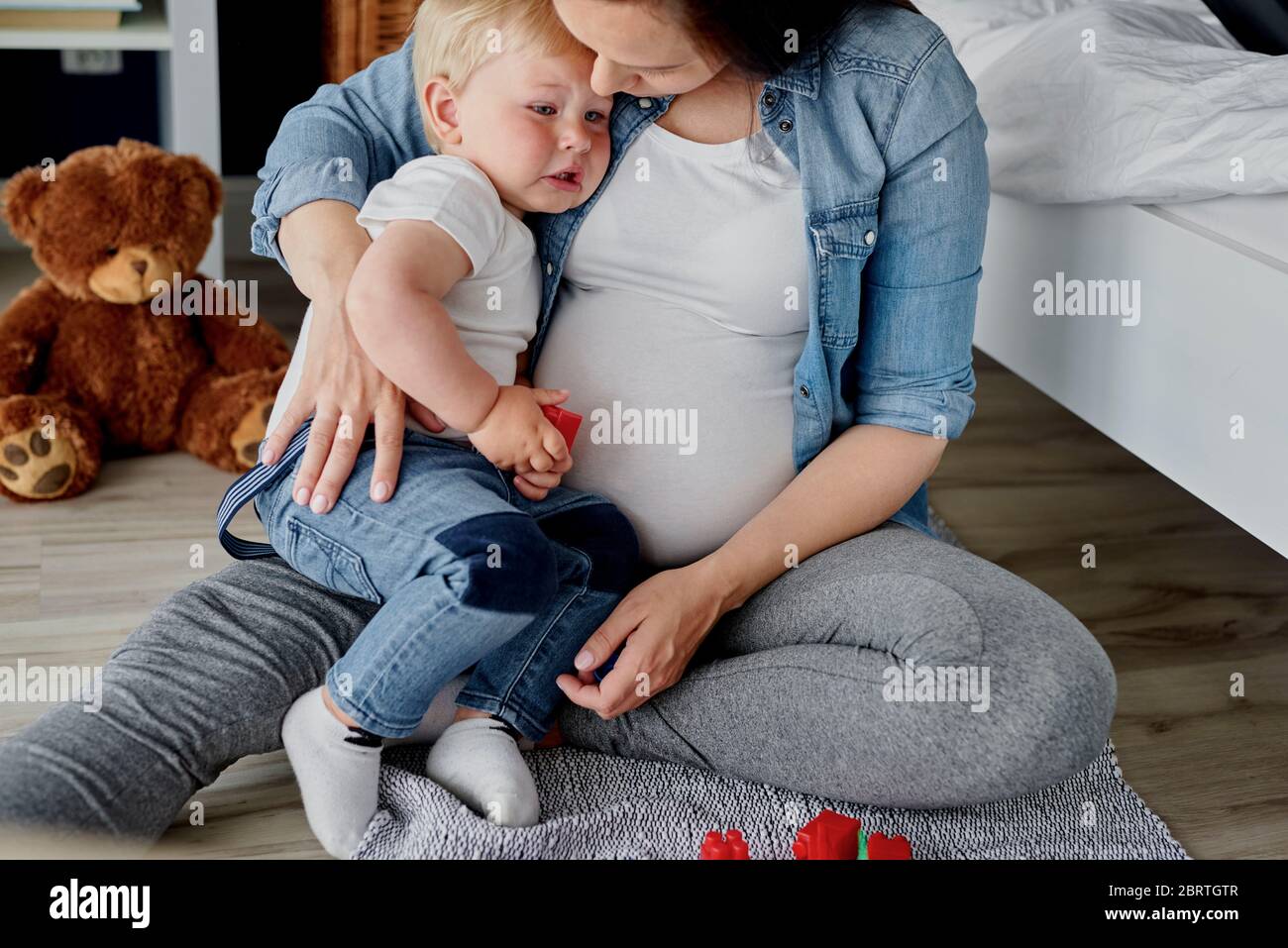 Trauriges Baby in den Armen seiner Mutter Stockfoto