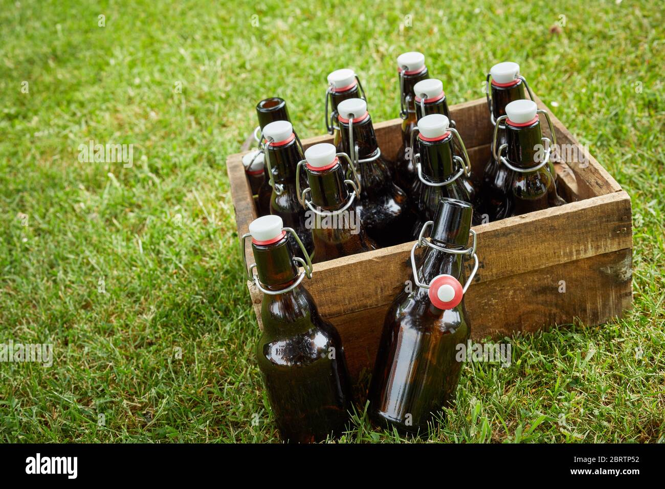 Holzkiste mit nicht etikettierten Flaschen Bier oder Lager an einem geneigten Winkel im Freien auf grünem Gras mit Kopie Raum für einen Sommer Picknick Stockfoto