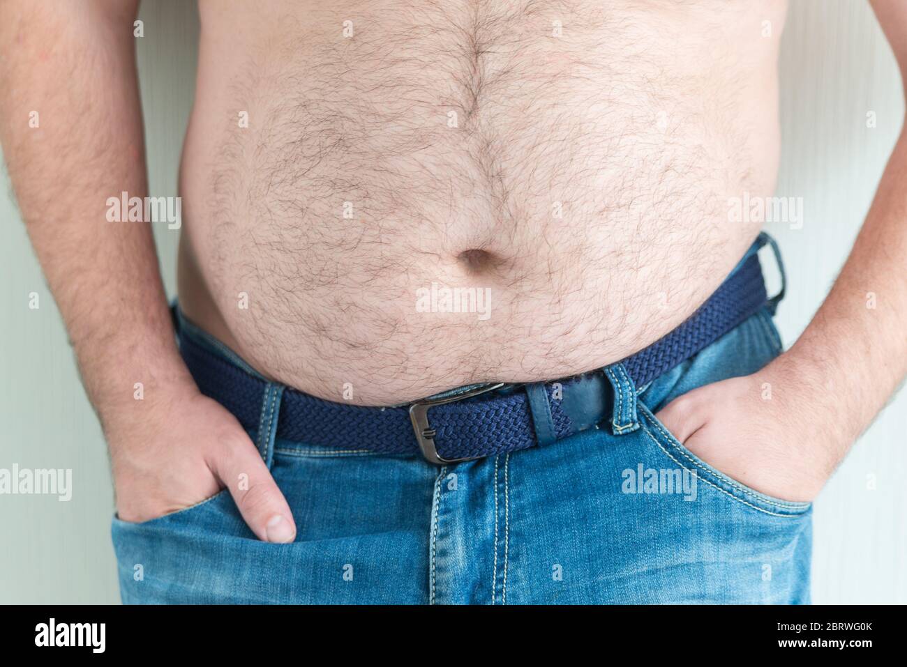 Nahaufnahme von fetten haarigen Glocken. Der Mann hält seine Hände in Jeans-Taschen. Übergewicht und ungesunde Konzept Stockfoto