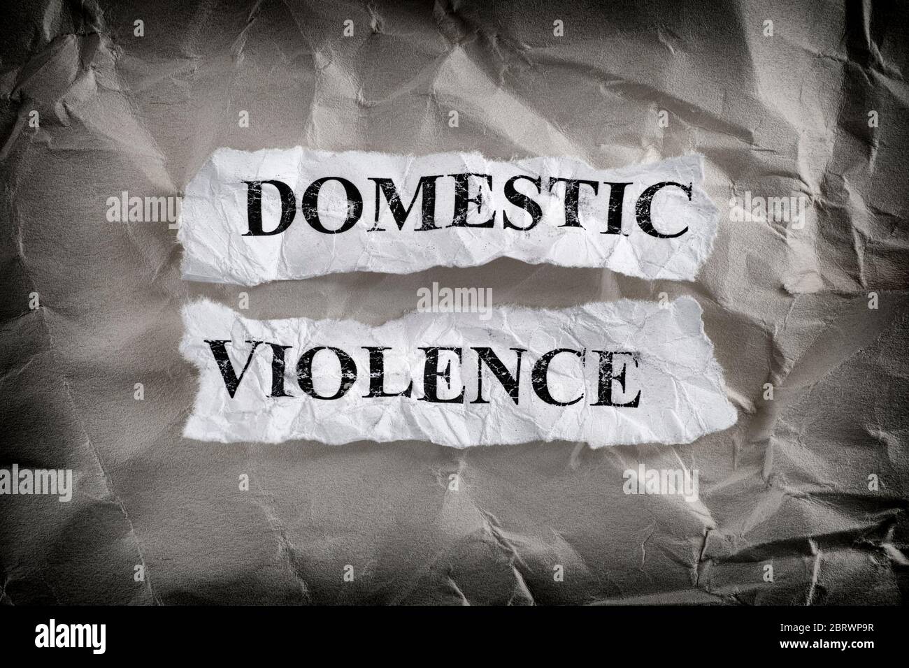 Häusliche Gewalt. Zerrissene Papierstücke mit den Worten häusliche Gewalt auf zerknittertem Papierhintergrund. Konzept Bild. Nahaufnahme. Stockfoto