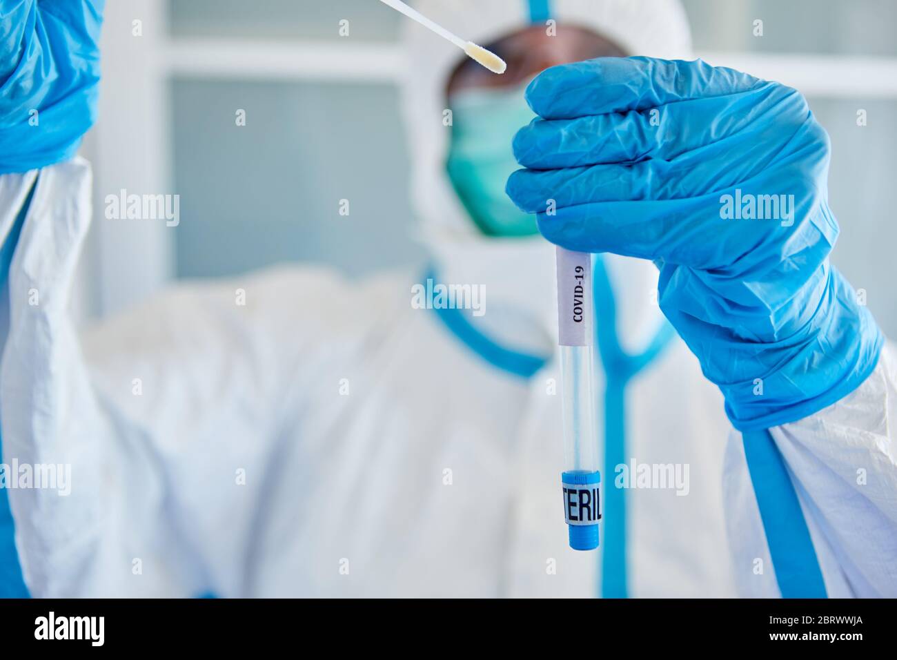 Medic in Schutzkleidung verpackt Rachenabstrich aus Speichelprobe für Covid-19-Test Stockfoto