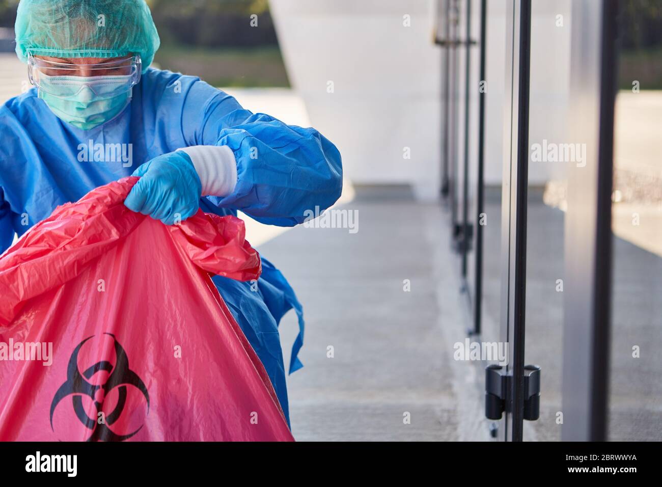 Reiniger kontrolliert die Entsorgung gefährlicher Abfälle in der Klinik während der Coronavirus-Pandemie Stockfoto
