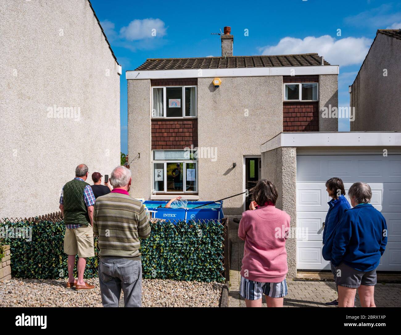 North Berwick, East Lothian, Schottland, Großbritannien, 22. Mai 2020. Fundraising Schwimmen im Planschbecken: Jane McMenemy, 40 Jahre, schwimmt 5 Meilen in ihrem Vorgarten, verbunden mit einem Widerstandsband, um Geld zu sammeln, um Tiere im Edinburgh Zoo durch nur geben während der Covid-19 Coronavirus Pandemie gesperrt füttern. Ihr Ziel von £500 wurde erreicht, bevor das Schwimmen begann. Die Pools sind 10 Meter lang und 75cm tief. Bei 1 Meile pro halbe Stunde sollte es 2.5 Stunden dauern, bis das Ziel erreicht ist. Nachbarn klatschen und feuern sie an. Stockfoto