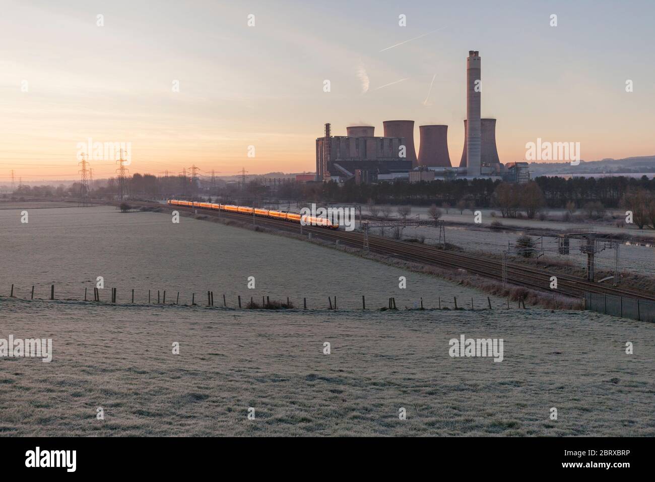 Ein London - Manchester Piccadilly Virgin Trains Westküste Pendolino Pässe Rugeley power station (südlich von Stafford), wenn die Sonne aufgeht Stockfoto