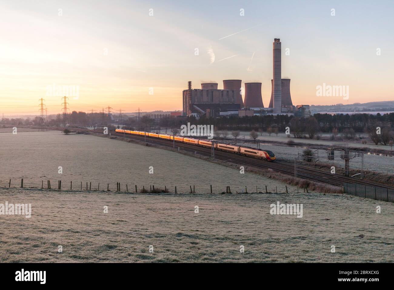 Ein London - Manchester Piccadilly Virgin Trains Westküste Pendolino Pässe Rugeley power station (südlich von Stafford), wenn die Sonne aufgeht Stockfoto