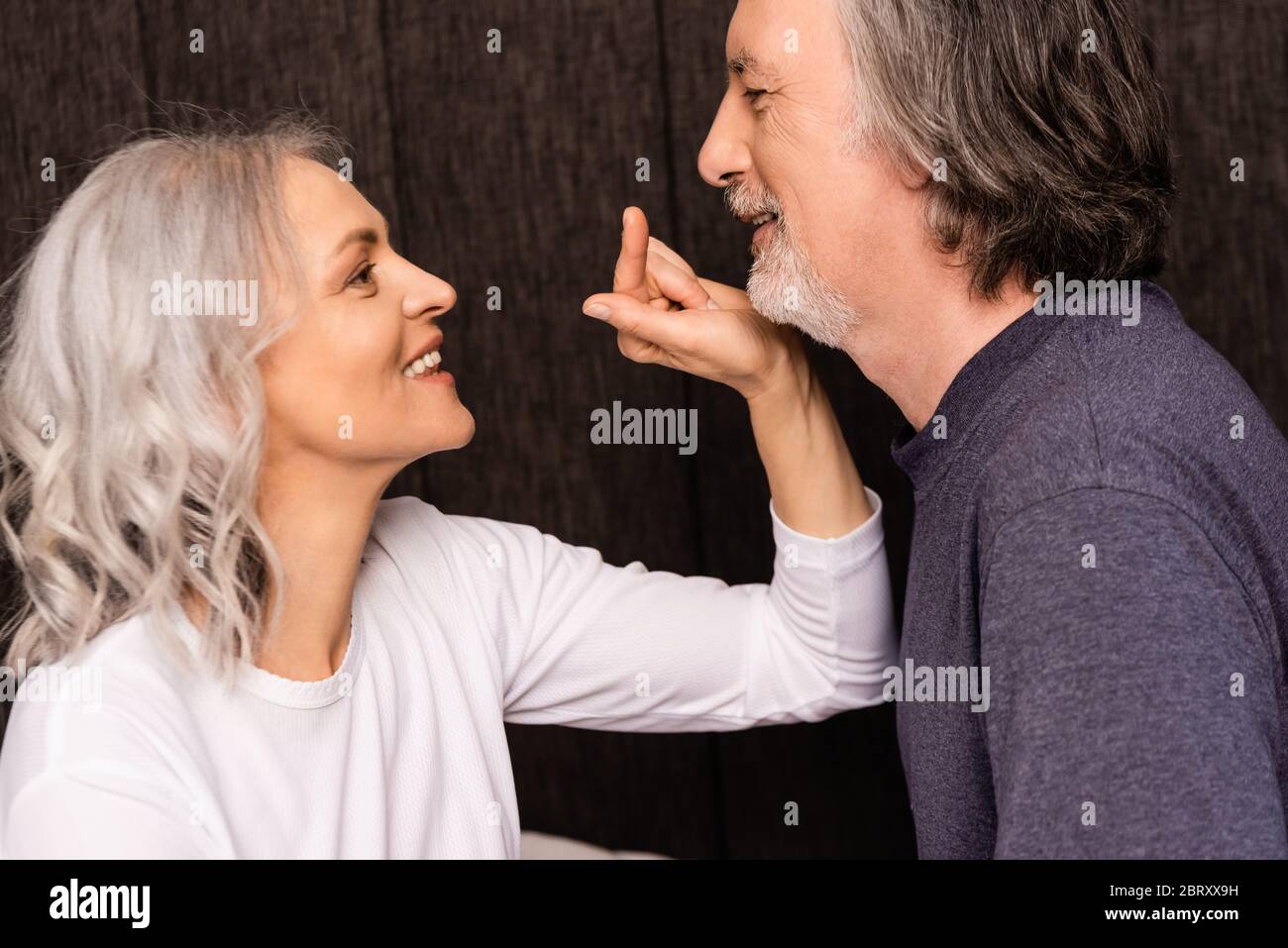 Seitenansicht der glücklichen reifen Frau zeigt mit Finger auf Ehemann Stockfoto