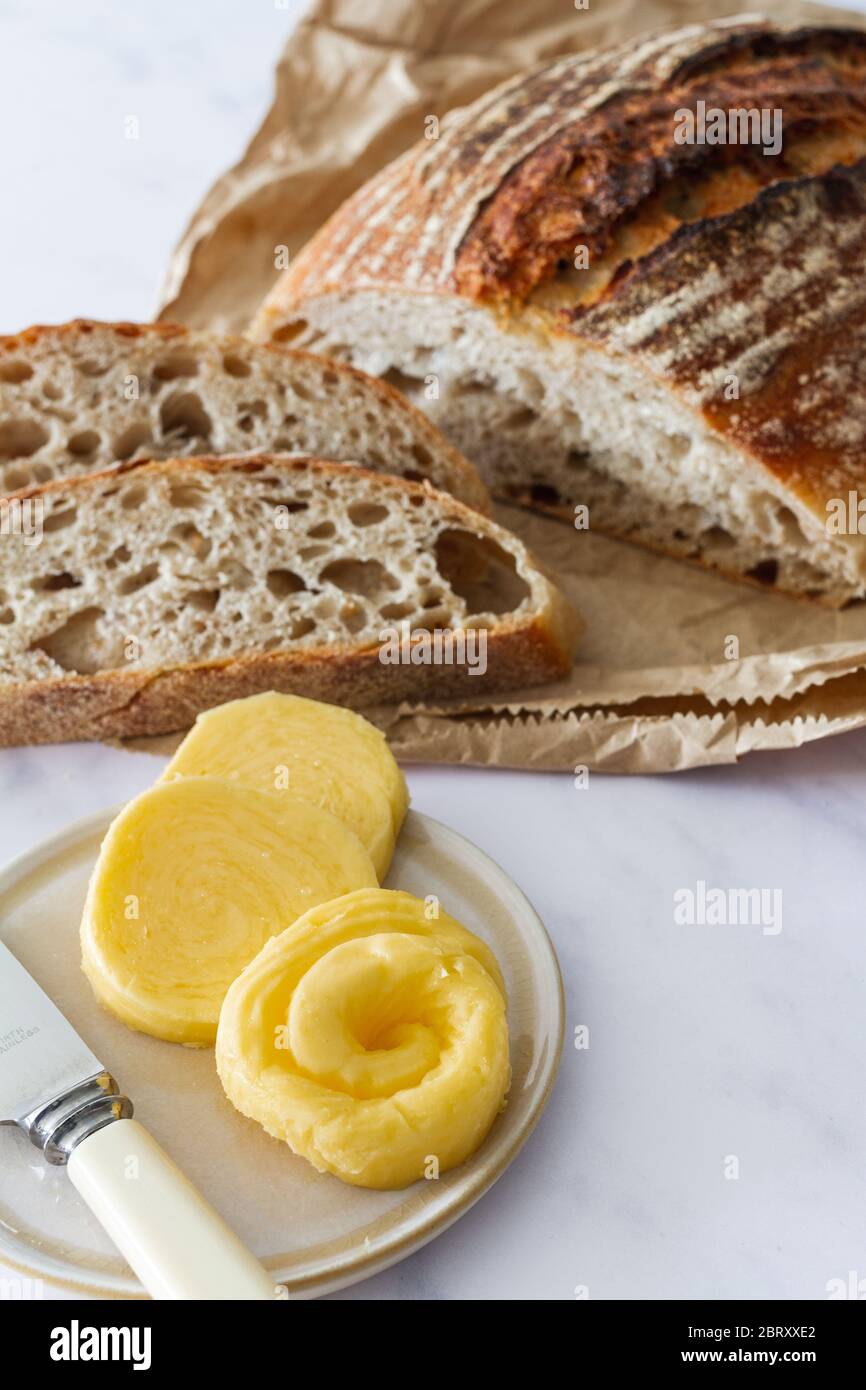 Frisches Brot mit Sauerteigbrot mit geschnittenen Scheiben und einer Schale frischer Butter Stockfoto