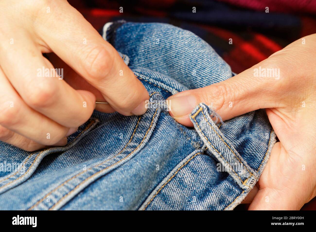 Nahaufnahme der Frau Hand mit einer Nadel, die Jeans nähen. Stockfoto