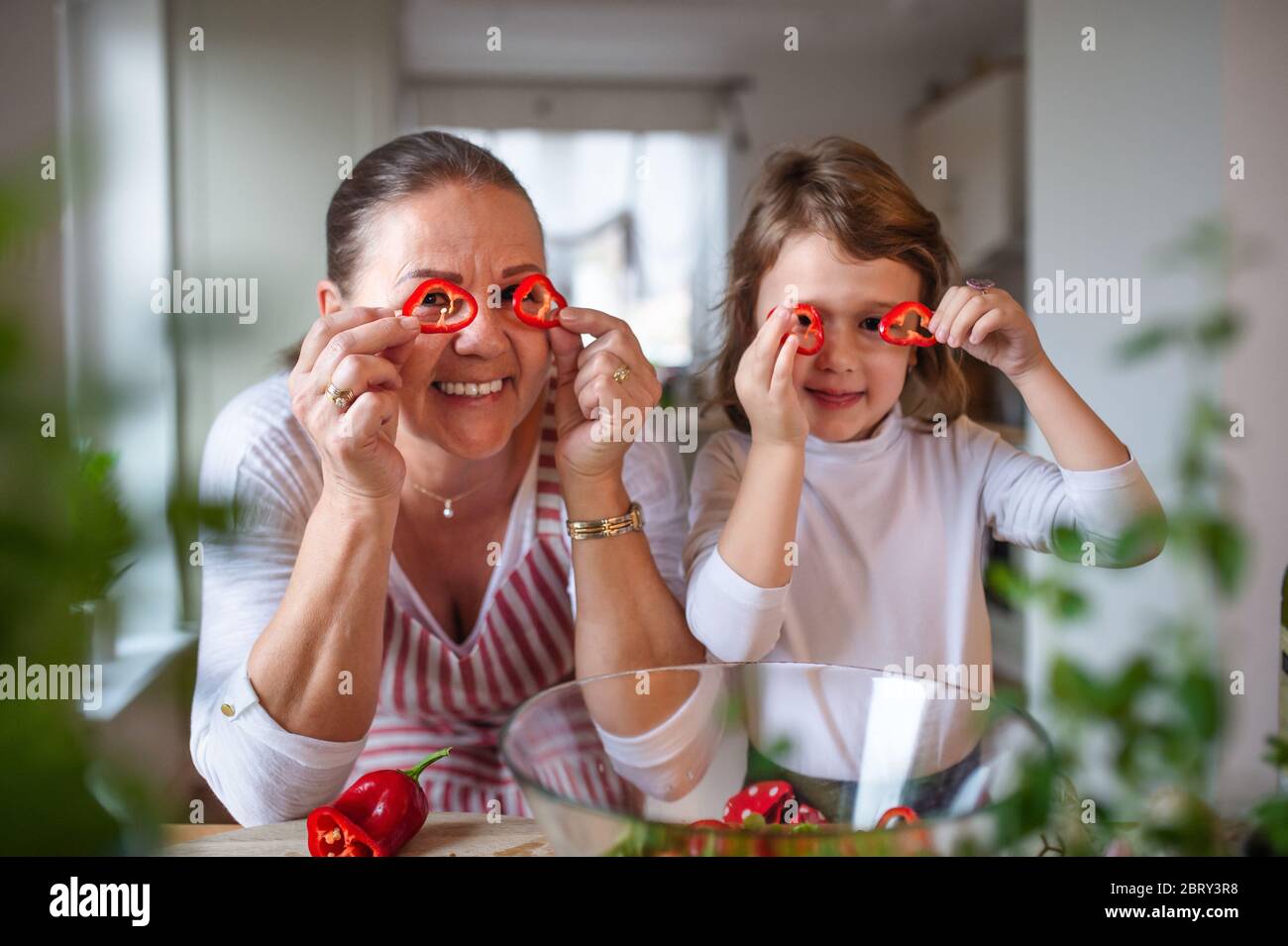 Kleines Mädchen mit älterer Großmutter in der Küche drinnen zu Hause, Spaß haben. Stockfoto