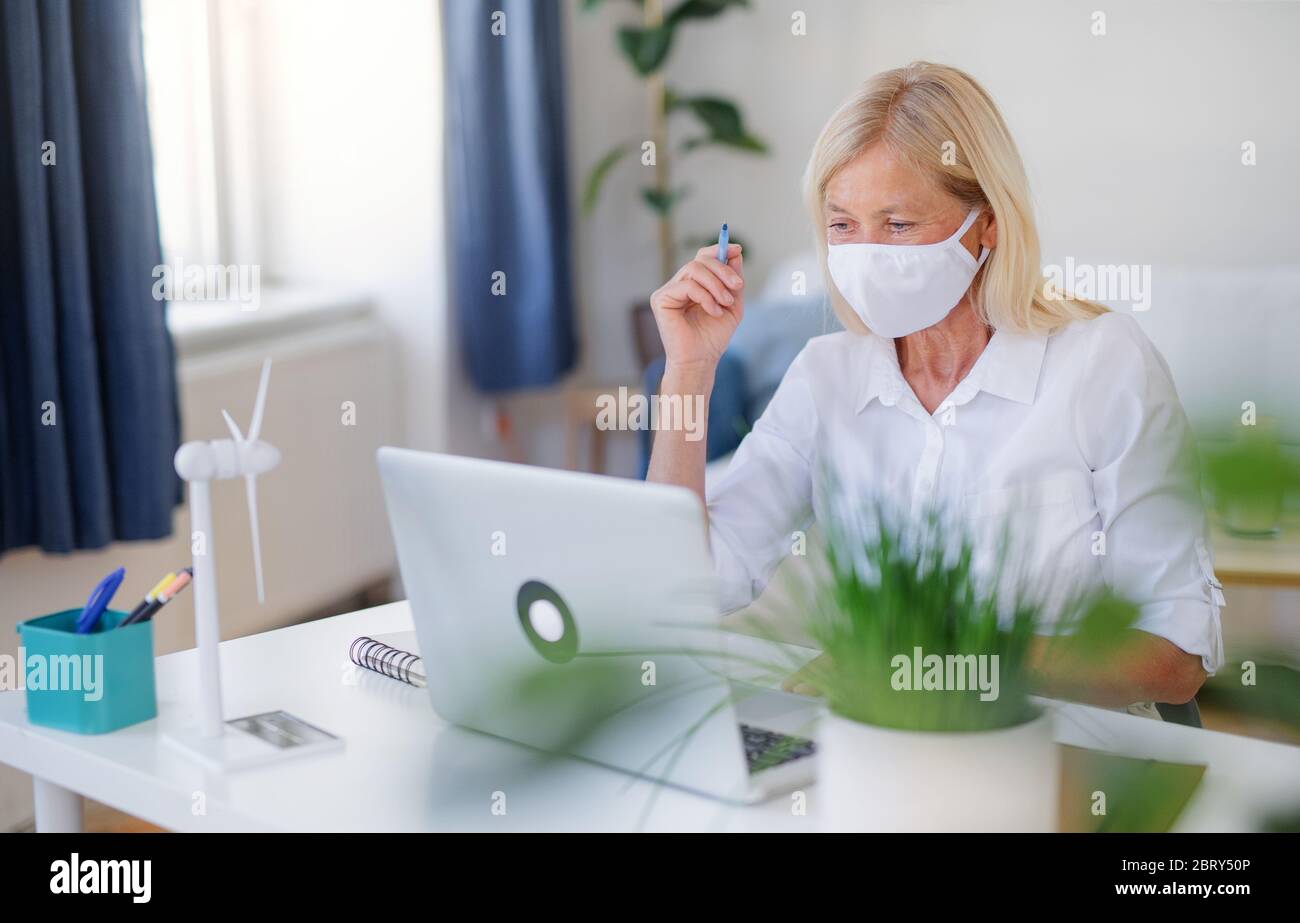 Senior Frau Ingenieurin mit Gesichtsmaske und Laptop im Büro, arbeiten. Stockfoto