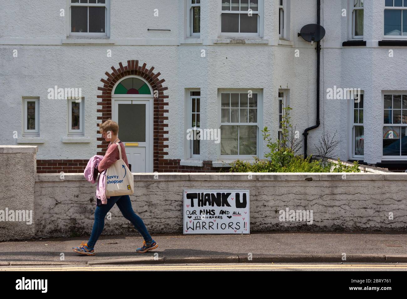 Eine Frau geht an einem Schild vor einem Haus in Wales, Großbritannien vorbei und dankt NHS-Mitarbeitern und Schlüsselarbeitern während der Coronavirus-Pandemie Stockfoto