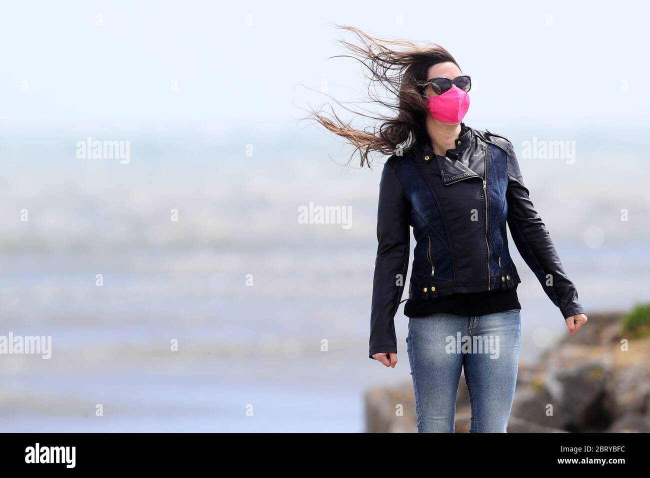 Eine Frau posiert, als eine Freundin ein Foto auf der Bull Wall in Dublin macht, während die windigen Bedingungen andauern. Stockfoto