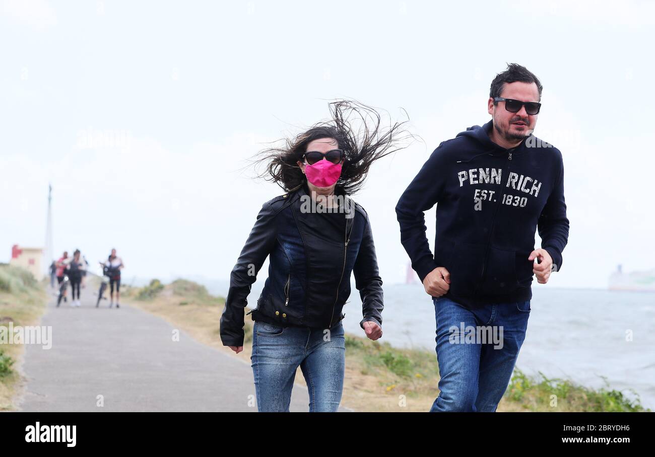 Ein Mann und eine Frau laufen darauf hin, während die windigen Bedingungen auf der Bull Wall in Dublin einziehen. Stockfoto