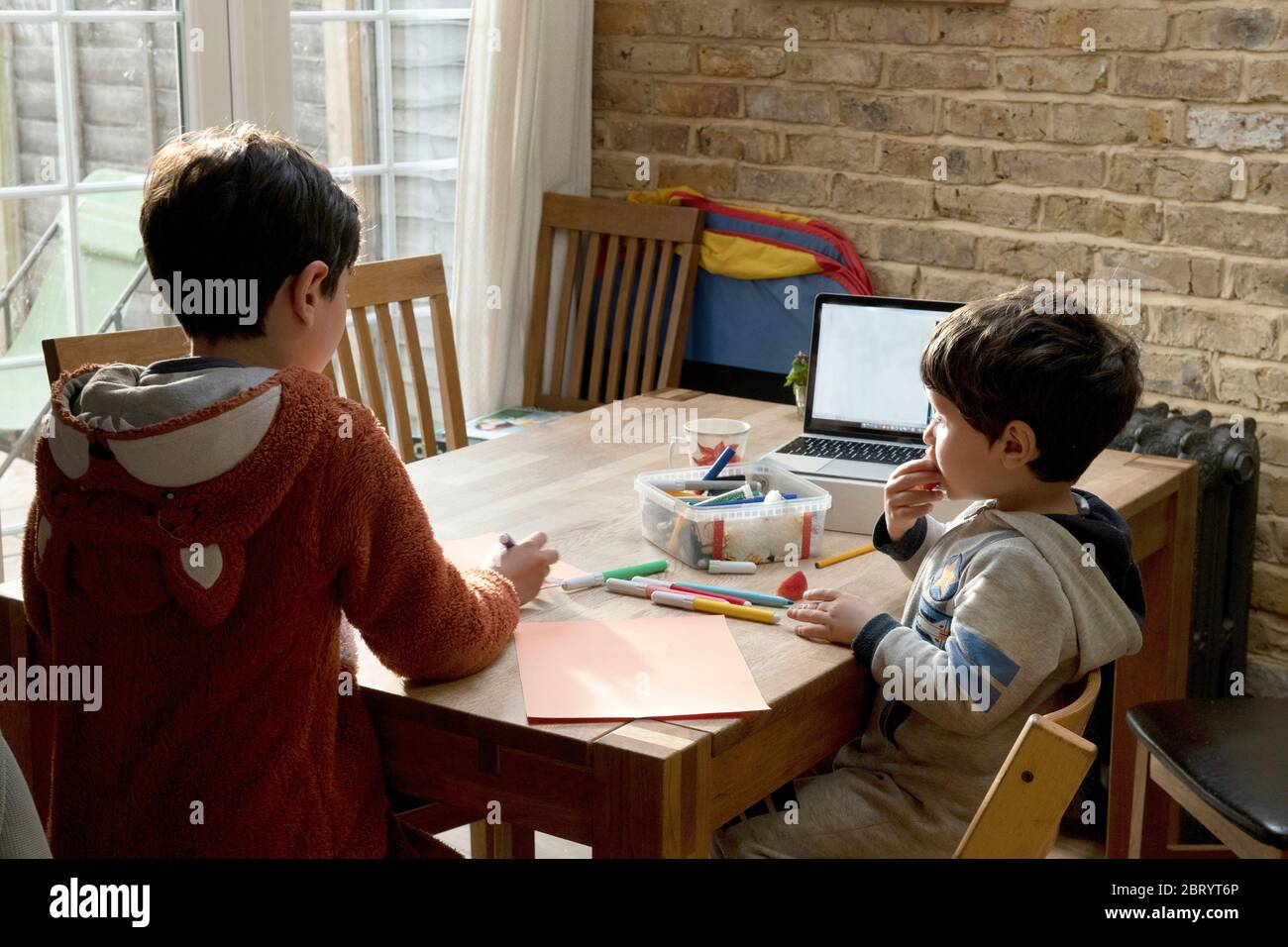 Zwei Brüder saßen an einem Tisch, zeichneten mit Filzstiften, Zeichnungen, um dem NHS-Gesundheitsdienst zu danken. Stockfoto