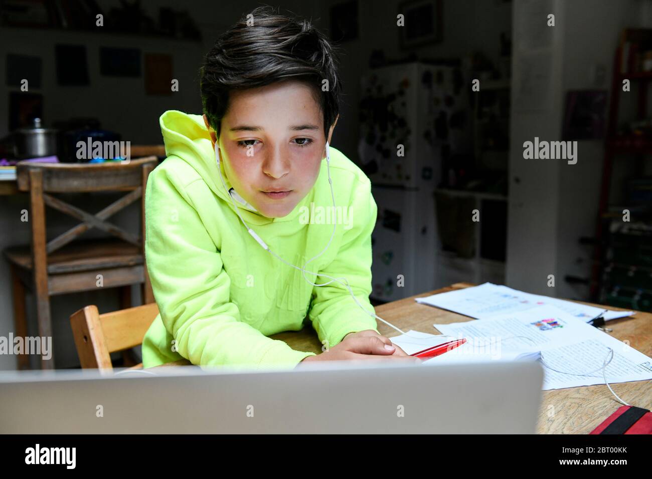 Ein Junge sitzt an einem Schreibtisch mit einem Laptop für eine interaktive Lerneinheit, zu Hause Schule, hart arbeiten. Stockfoto