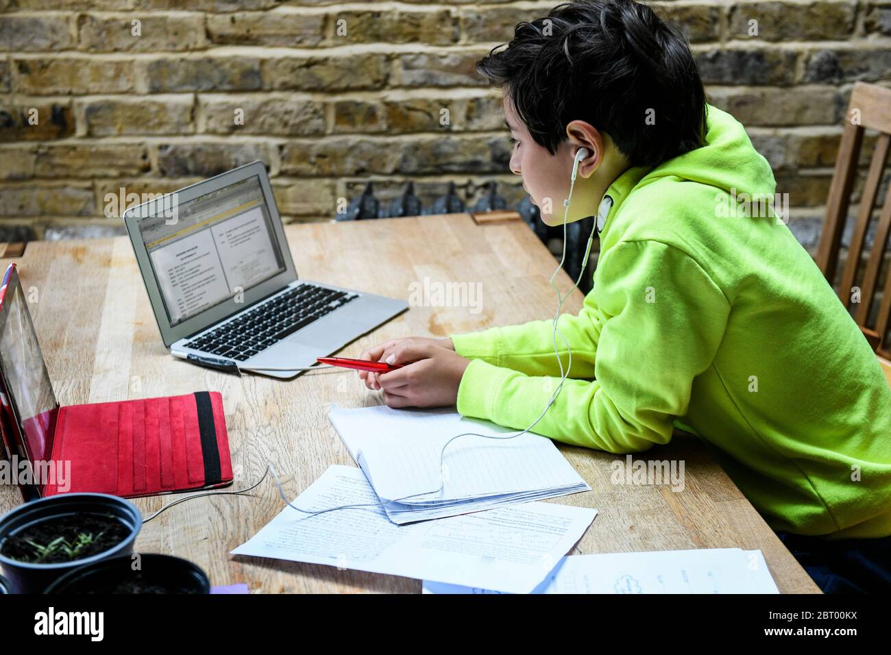 Ein Junge sitzt an einem Schreibtisch mit einem Laptop für eine interaktive Lerneinheit, zu Hause Schule, hart arbeiten. Stockfoto