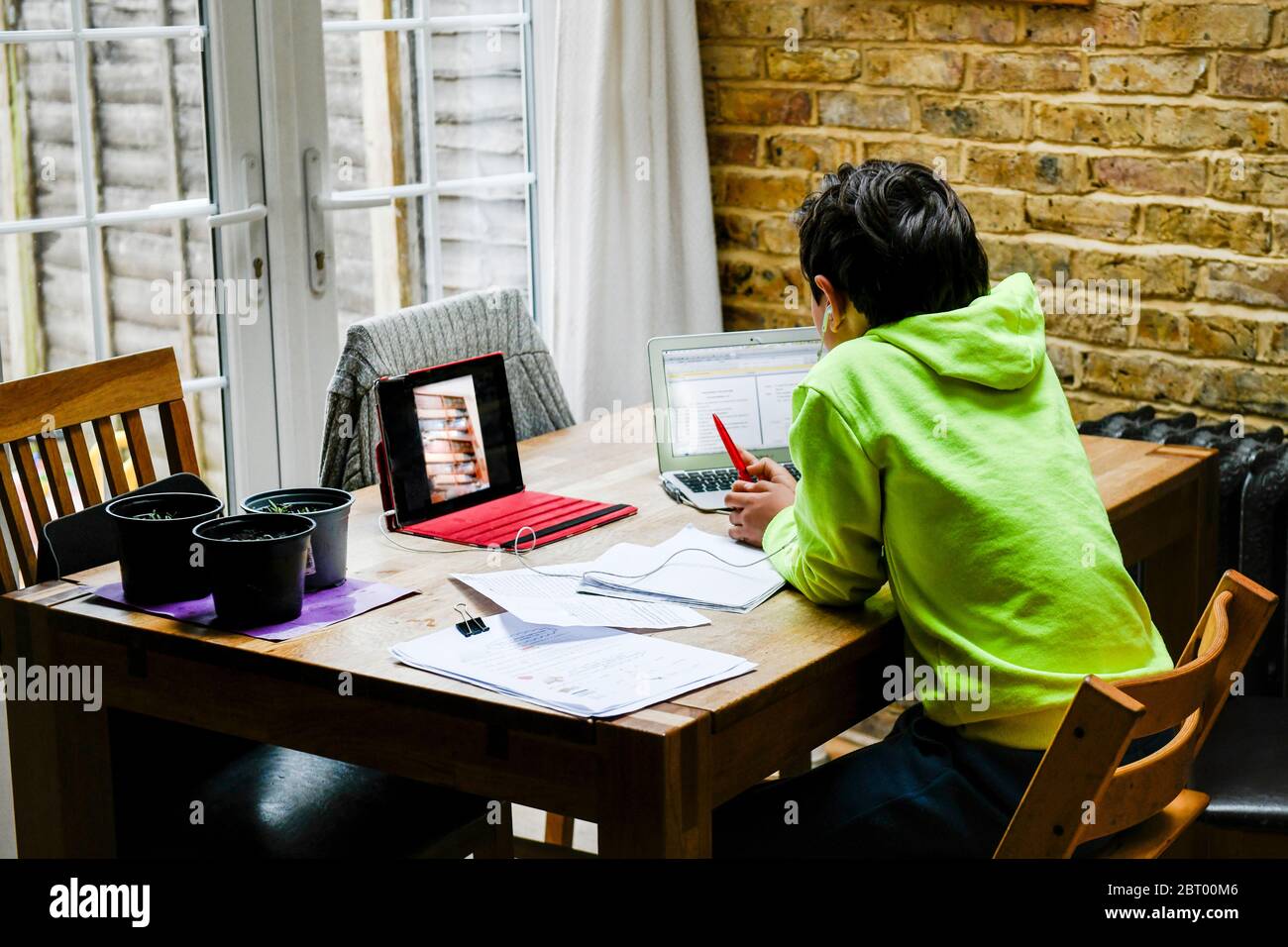 Ein Junge sitzt an einem Schreibtisch mit einem Laptop für eine interaktive Lerneinheit, zu Hause Schule, hart arbeiten. Stockfoto