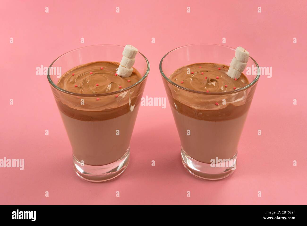 Zwei Gläser trendy koreanischen Dalgona Kaffee mit Marshmellows auf rosa Hintergrund Stockfoto