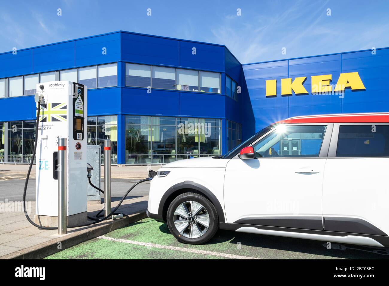 Großes gelbes IKEA Logo-Schild an der Seite des blauen IKEA-Lagers mit einem Elektroauto, das Nottingham East Midlands England GB Europa lädt Stockfoto