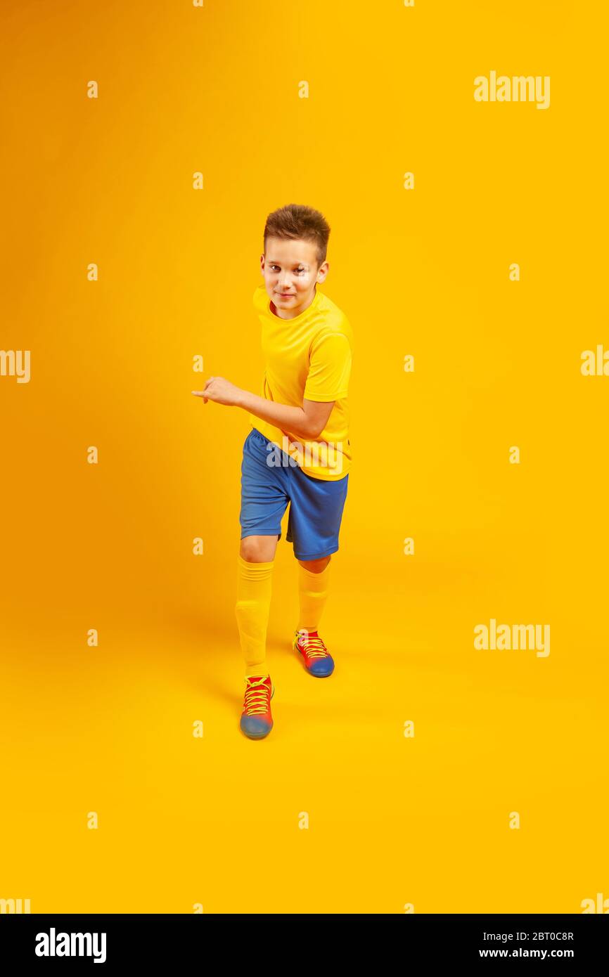 Laufjunge in Fußballuniform auf einem gelben Stockfoto