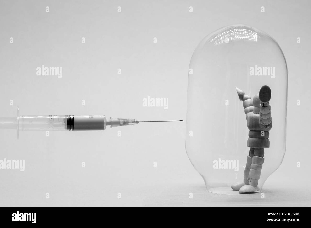 Schwarzweiß-Bild. Ein Mann in einer Glasflasche, der Immunität symbolisiert, versucht sich vor einer Impfung gegen das Coronavirus zu schützen. Stockfoto