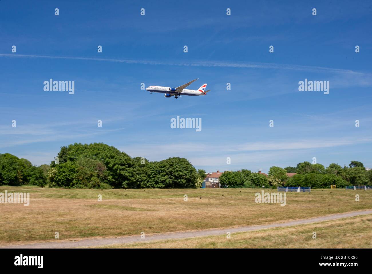 British Airways Jet-Flugzeug auf dem Weg zu landen über einem grünen Park in Cranford. Flugzeuge landen in London Heathrow über dem Spielbereich Stockfoto