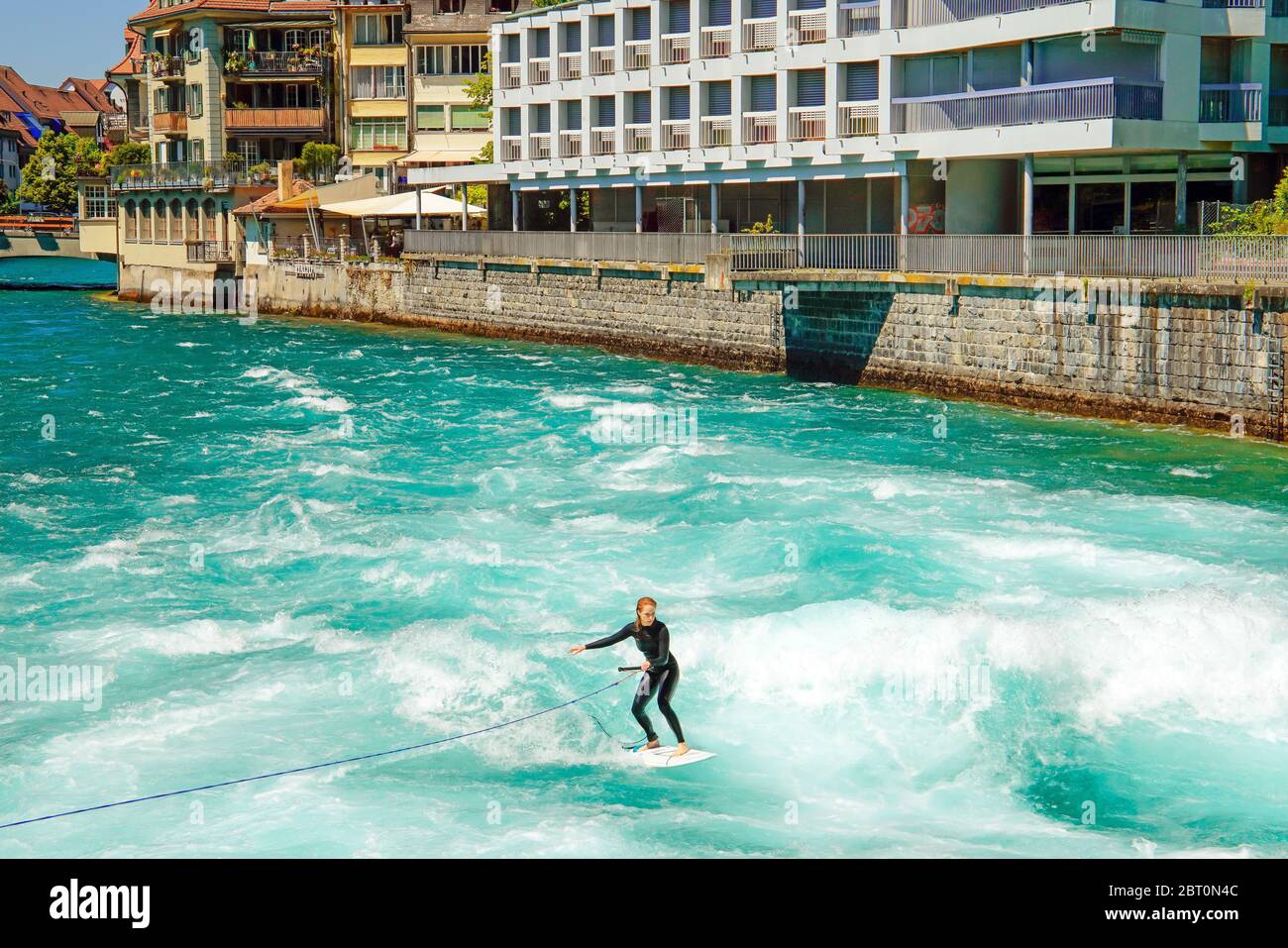 Surfen auf den schnellen Wellen, die entstehen, wenn die Schleusentore am Aarau in der Innenstadt von Thun, Kanton Bern, Schweiz, geöffnet sind. Stockfoto