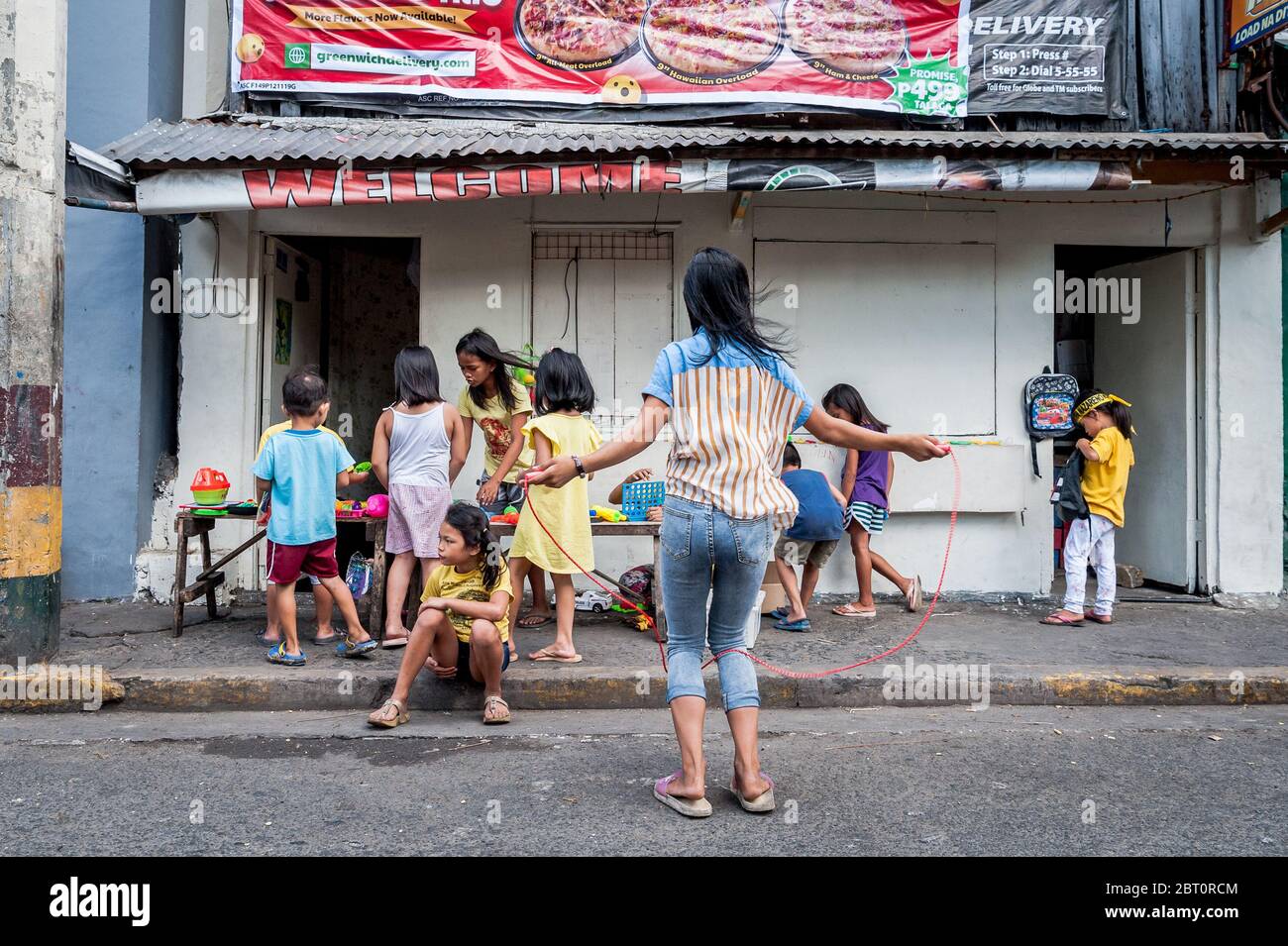 Junge philippinische Kinder spielen auf der Straße in der alten ummauerten Stadt Intramuros, Manila, Philippinen. Stockfoto