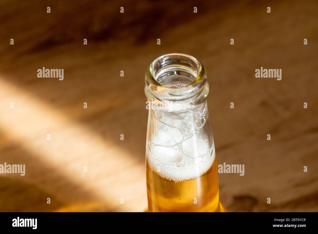 Die Oberseite einer Flasche erfrischendes Bier in der Sonne während Ihres Aufenthalts zu Hause an einem heißen Tag während der COVID-19 Sperre Stockfoto